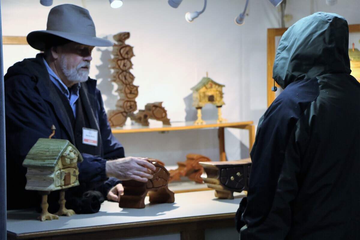 Steven Martin, Carterville, Ill., shows his wares to an attendee at the annual Highland Art in the Park preview part Friday, Oct. 12.  VIPs got a preview of the artwork that was on sale throughout the weekend at the party.