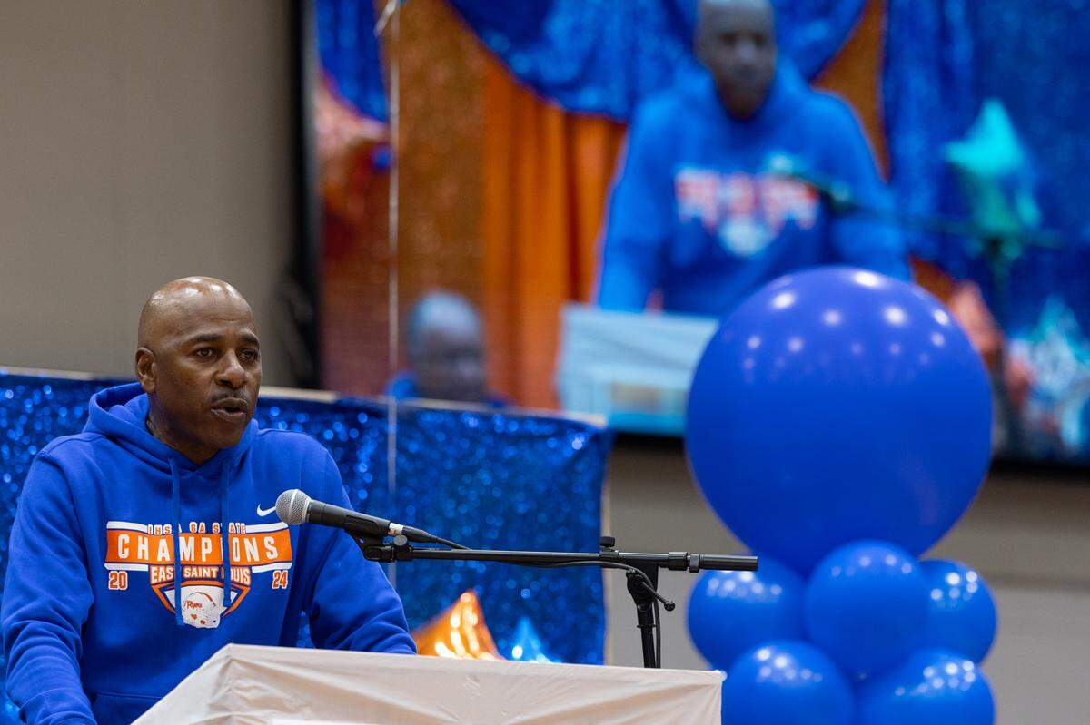 East St. Louis head coach Darren Sunkett speaks to East St. Louis High School while his own image is cast on the screen behind. Sunkett has led the Flyers to five championships and three in the last five seasons.