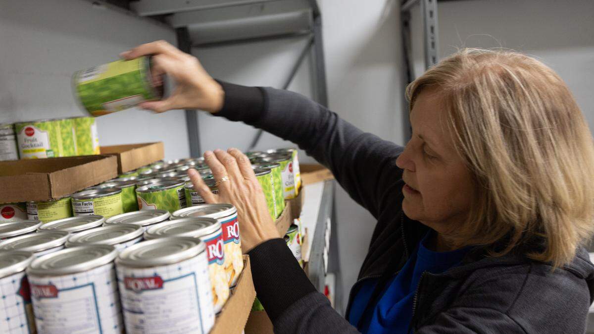 Volunteer Luanne Szopa stacks cans in the Community Interfaith Food Pantry in Belleville before it opens up to patrons for the day.