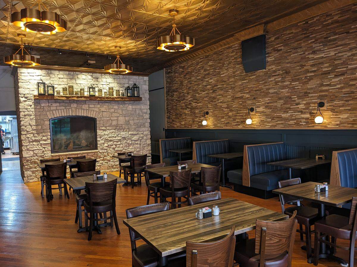 The main dining room at 1860 Public House features a detailed gold ceiling with flower-shaped lights with concealed ceiling fans.