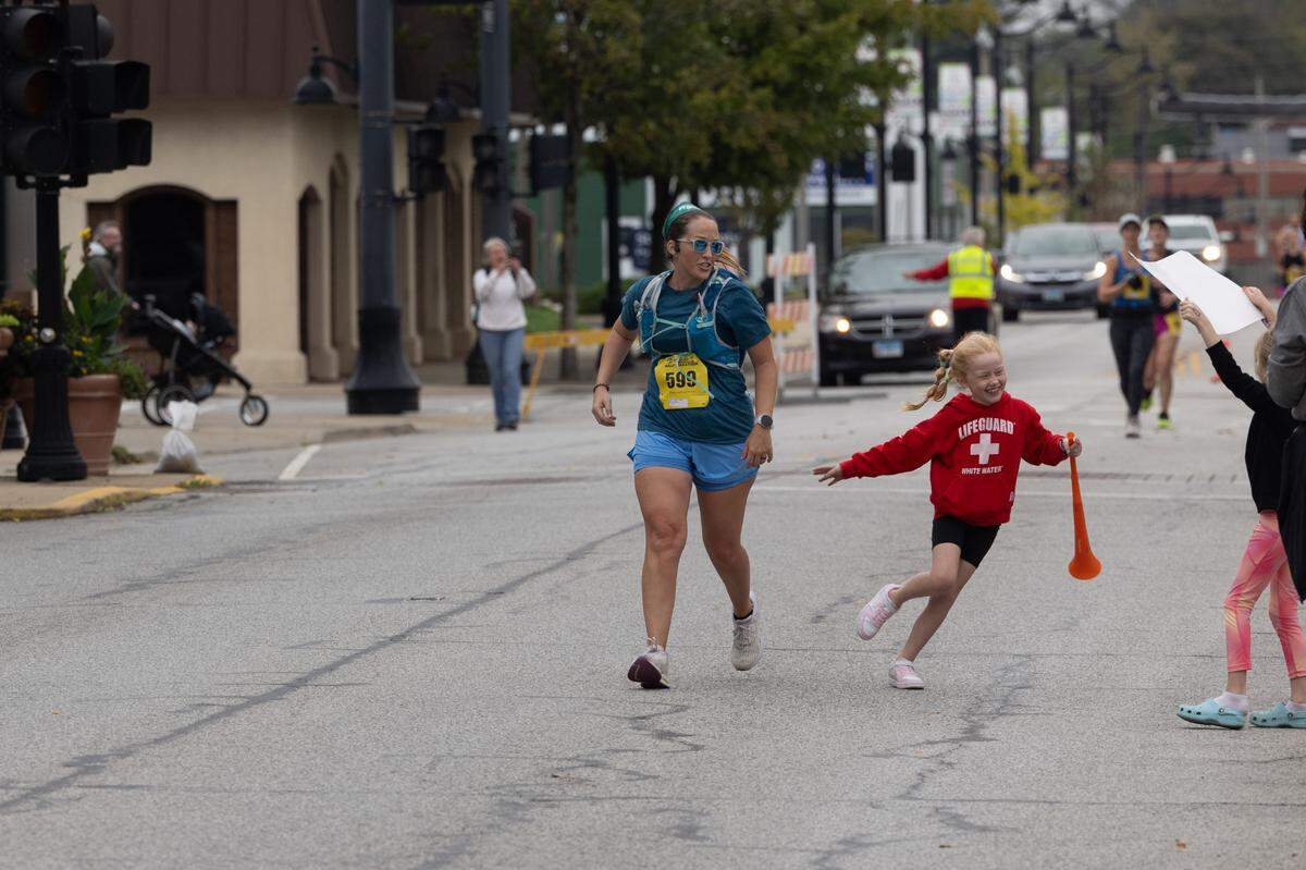 A child with a horn runs out to cheer on her mother at the Belleville Marathon on Sept. 28, 2024.