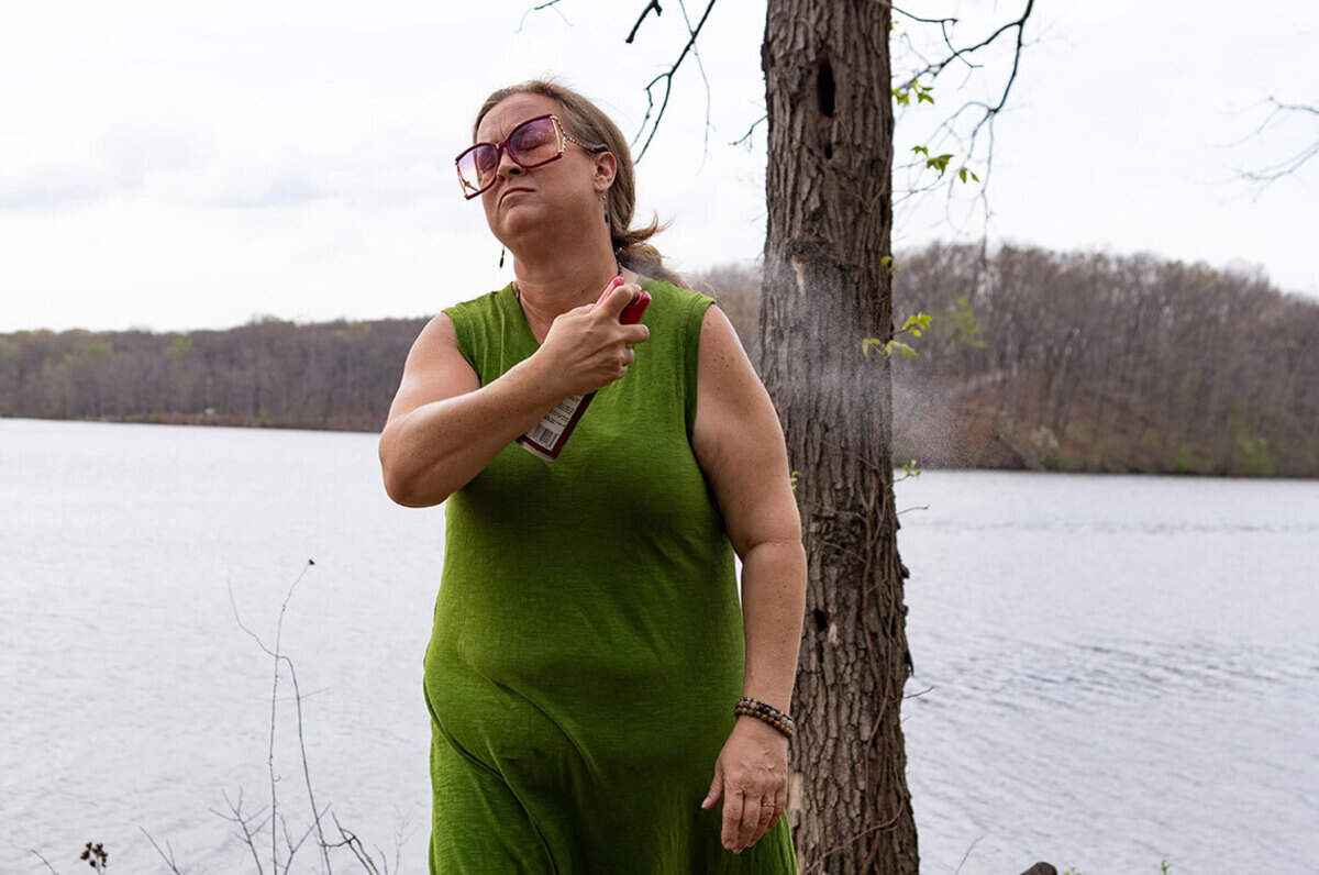 Amanda Allen Hall sprays herself with tick repellent April 4, 2026, at Lake Murphysboro State Park. Hall takes extra precaution after a tick bite led to alpha-gal.