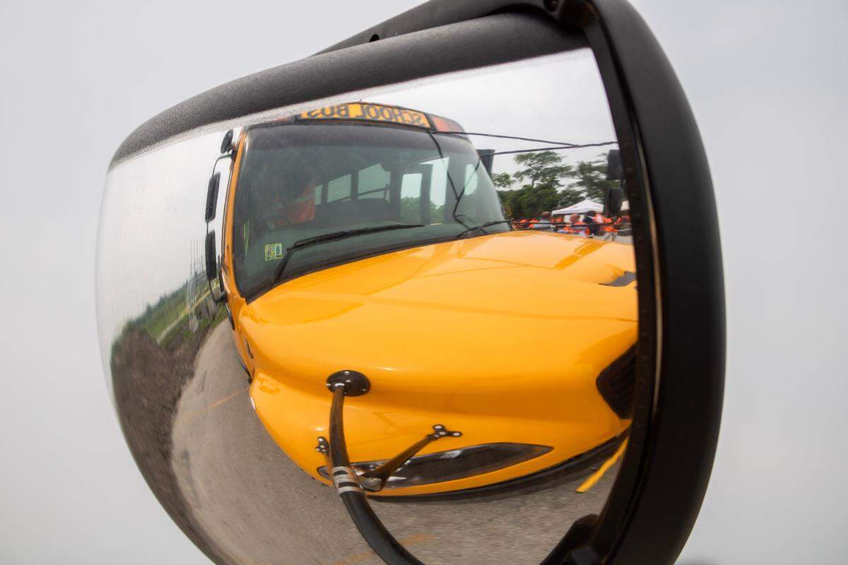 A yellow school bus can be seen through the reflection in its right side mirror.