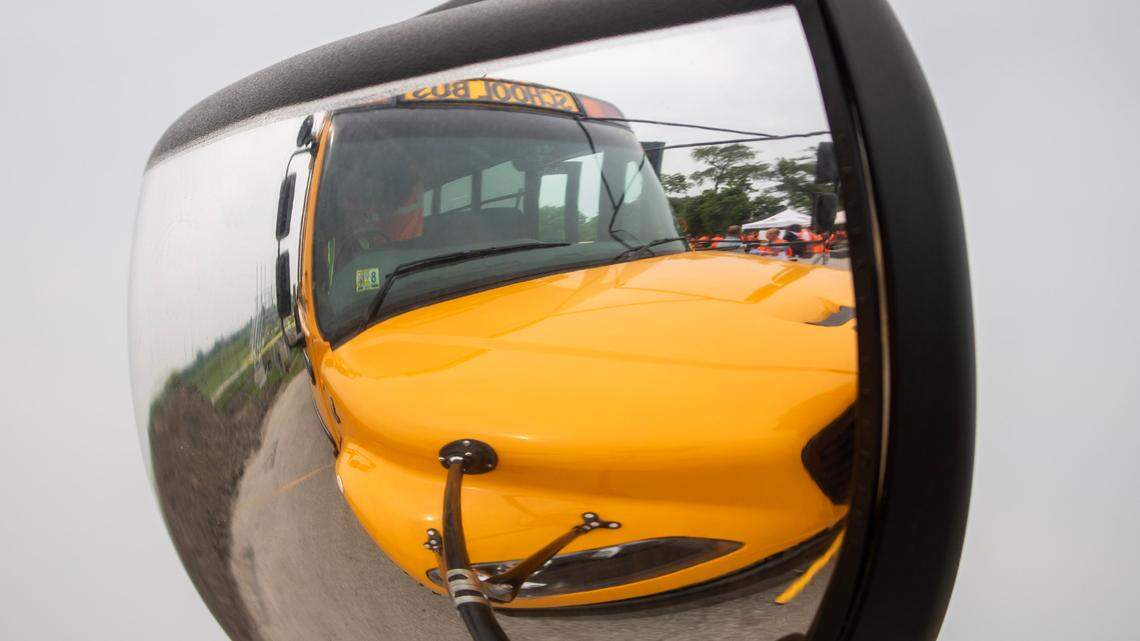 A yellow school bus can be seen through the reflection in its right side mirror.