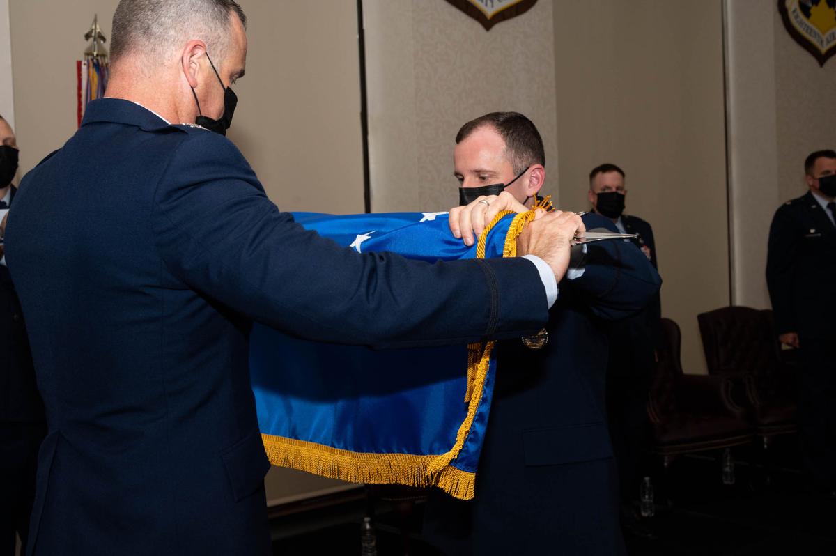 U.S. Air Force Col. Chris Robinson, 375th Air Mobility Wing Commander, and from Col. Kyle Baldassari, 375th Communications Group commander, furl the 375th CG guidon during the 375th CG inactivation ceremony on Scott Air Force Base. The furling and unfurling of guidons serves as a symbolic gesture for the activation, inactivation and realignment of units in the military.