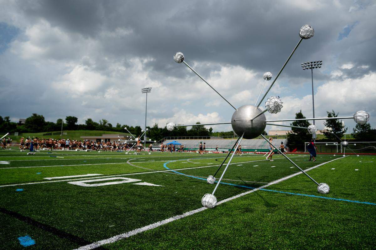 Oversized atom props used in the Boston Crusaders’ show “BOOM” are scattered across the football field on Tuesday, July 22, 2025, at Pattonville High School in Maryland Heights.