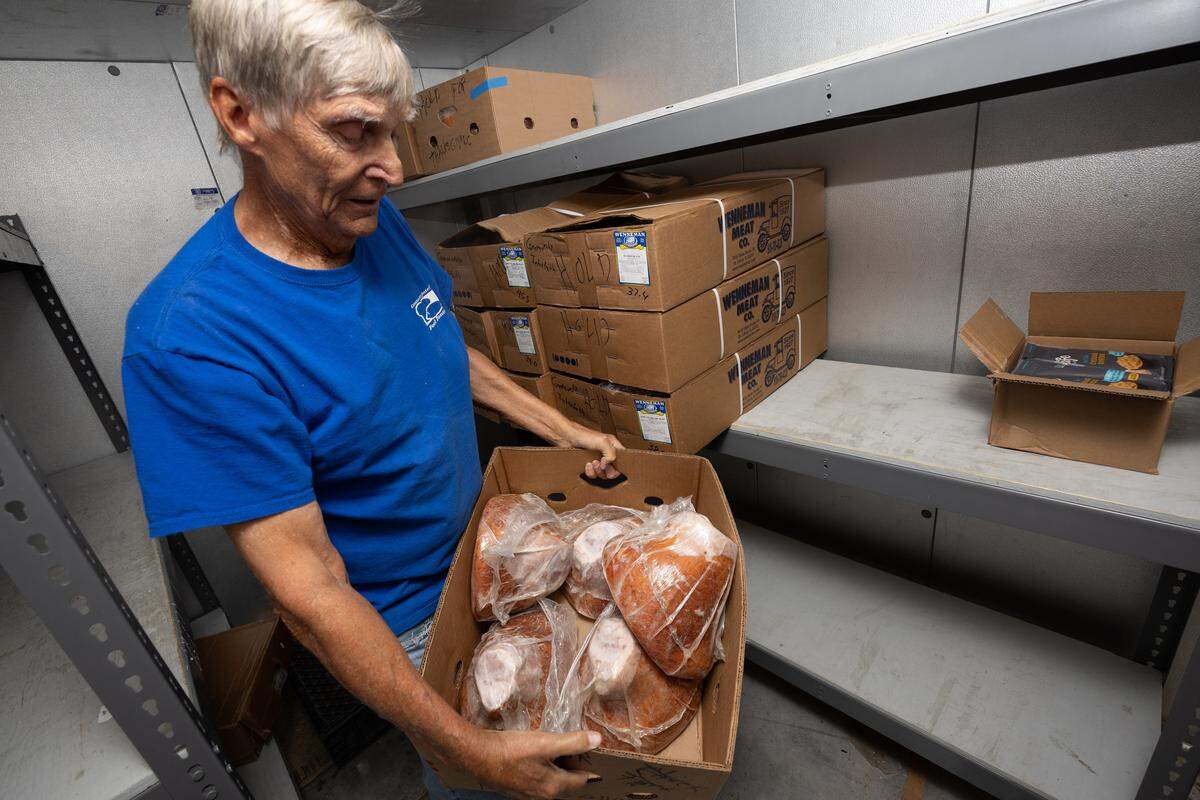 Volunteer Wes Frick holds a box of hams at Community Interfaith Food Pantry in Belleville. Frick said the pantry normally sends families home with “at least a few pounds of meat,” but have had less supply lately. “We’re saving these for Christmas and Thanksgiving,” Frick said. “Other than that we’re pretty short on meat.”