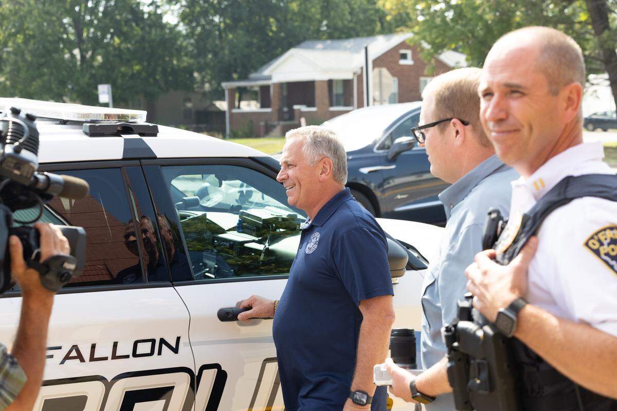 U.S. Rep. Mike Bost smiles as he enters a police cruiser while being asked questions from protesters in O’Fallon. Bost visited the metro-east city to speak with law enforcement but did not talk to protestors.