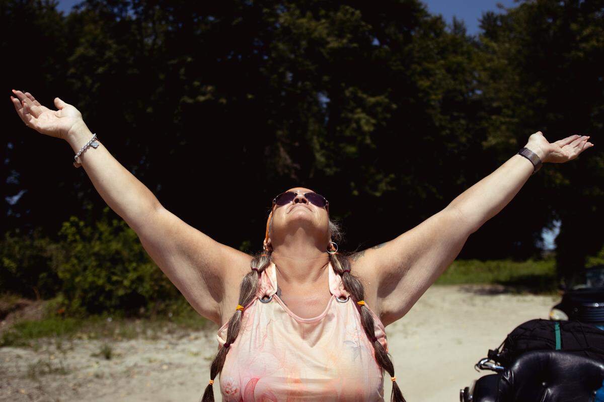 Tina Weber, 55, raises her hands to the sky as she waits for a ferry to come by on Saturday, Aug. 10, 2024, in southwestern Illinois. “I am soaking up the energy and asking the universe to fill her with love and joy to share with those who are not as blessed as she is.”