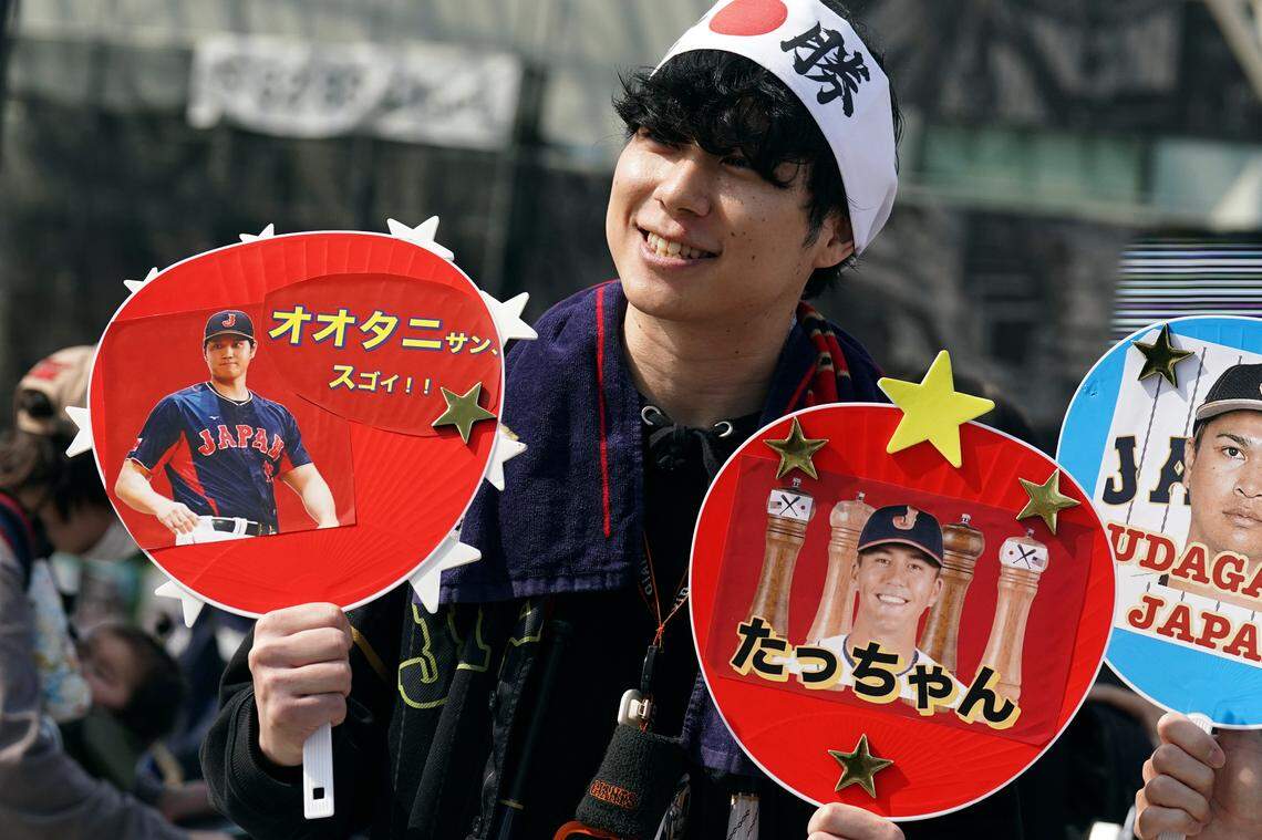 A fan of Japan’s Shohei Ohtani and Lars Nootbaar cheer prior to the Pool B game between Japan and China at the World Baseball Classic (WBC) at the Tokyo Dome Thursday, March 9, 2023, in Tokyo. The paper fans read in Japanese “Mr. Ohtani Great !!” and “Tacchan (Japanese nickname for Nootbaar).” Japanese baseball player Shohei Ohtani is arguably the game’s best player. But he’s more than just a baseball player. He’s an antidote for many in his native country. (AP Photo/Eugene Hoshiko)