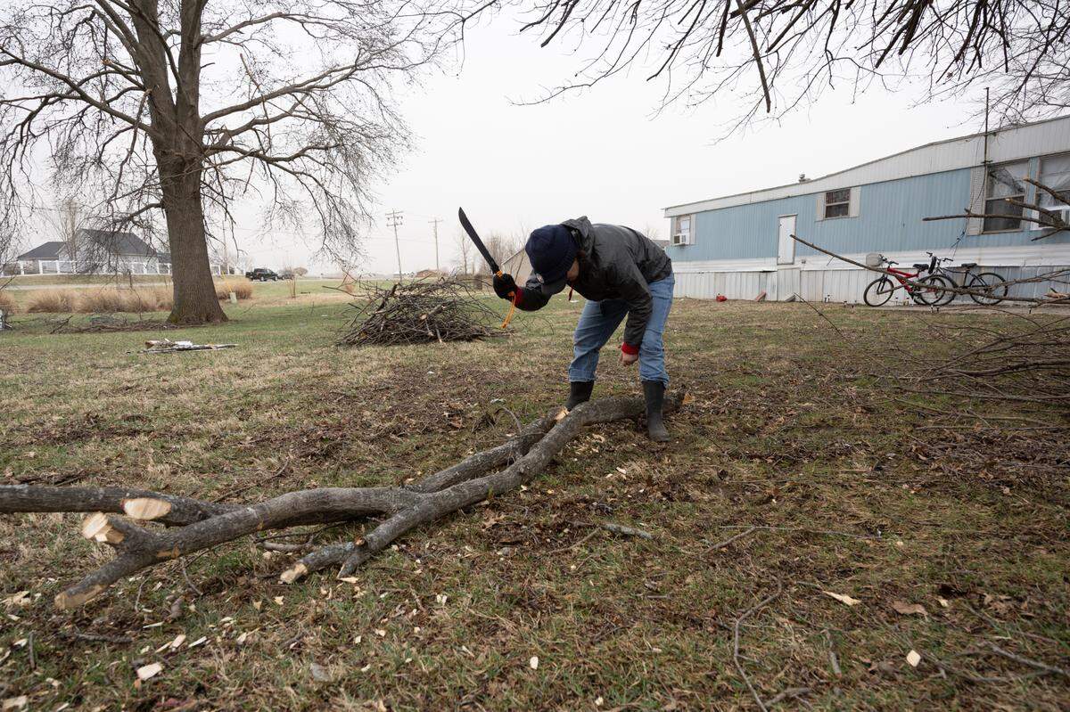 Amanda Hargis cuts up a fallen branch after a suspected tornado passed through her O’Fallon neighborhood on Friday night. ““It took 10 minutes to do all this. It was that fast,” Hargis said.