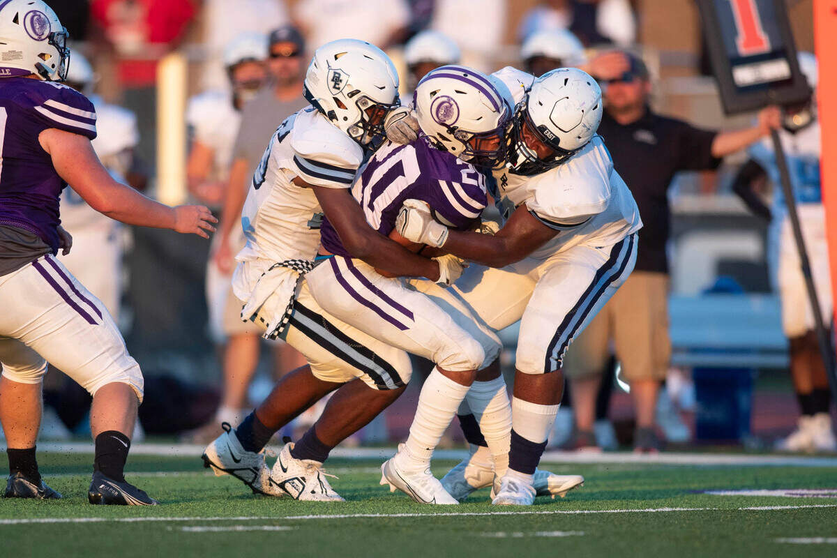 Belleville East’s Jaedon Coleman and OJ Mosey bring down Collinsville’s Isaiah Gordon during Friday night’s season opener for both teams. The Lancers ultimately prevailed 20-12.