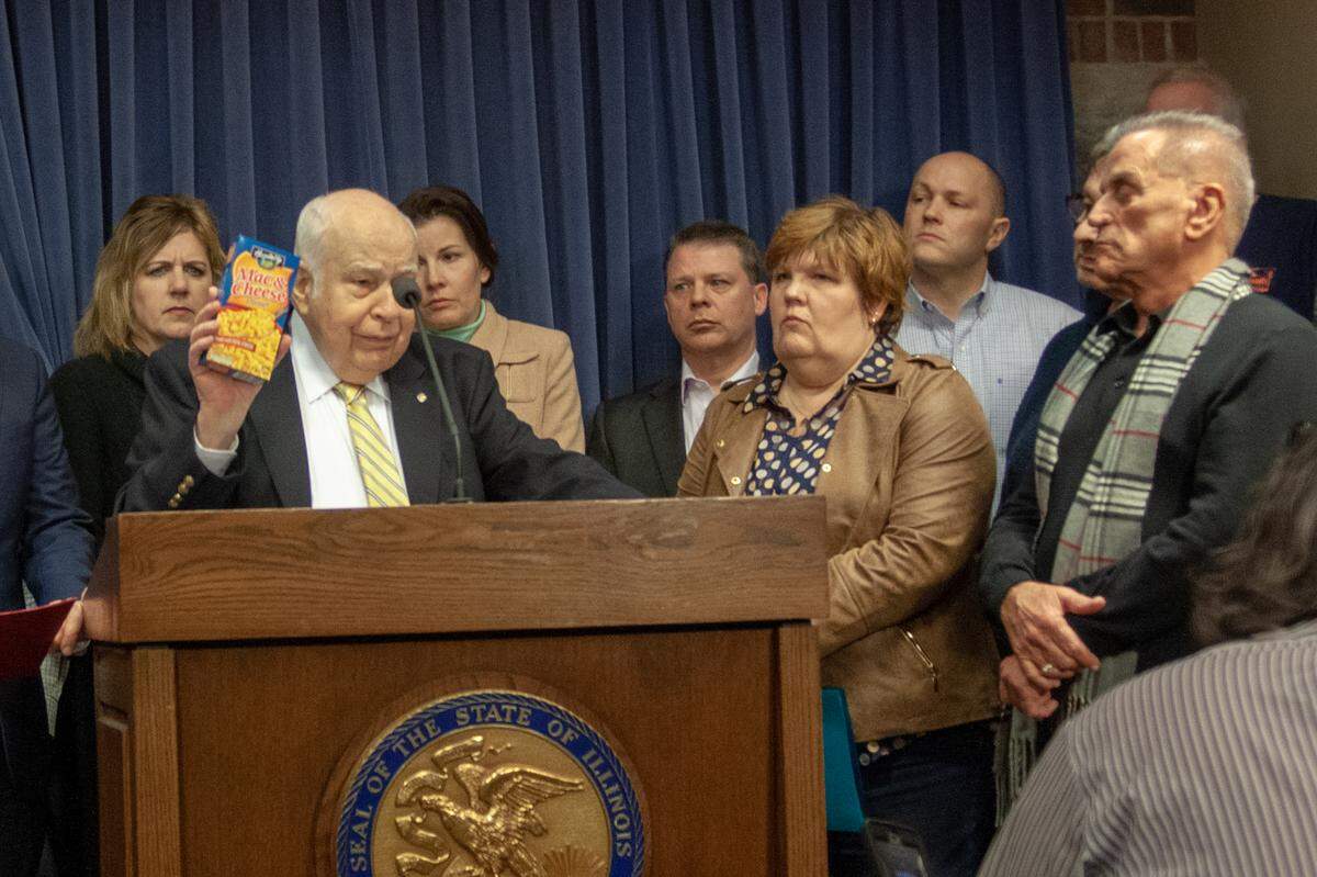Don Welge, president and CEO of Gilster-Mary Lee, a family and privately held food manufacturer headquartered in Chester, holds up a box of macaroni and cheese, which he said could become a money-losing product for his company if the minimum wage increase legislation becomes law. At right is Sandy Schoenborn, owner of the Lincoln Theatre in Belleville.