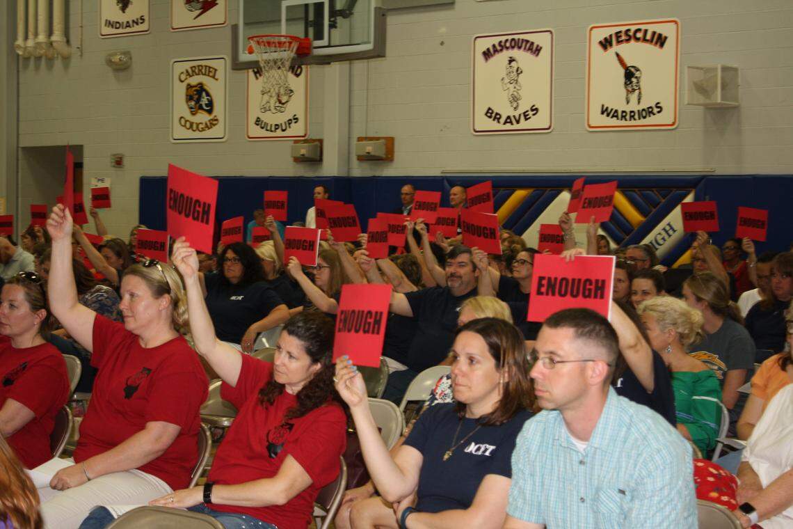 Every time O'Fallon School District 90 board member Steve Springer spoke during the board meeting Tuesday night about 120 teachers held up uniform red signs with black letters reading, 'Enough.'