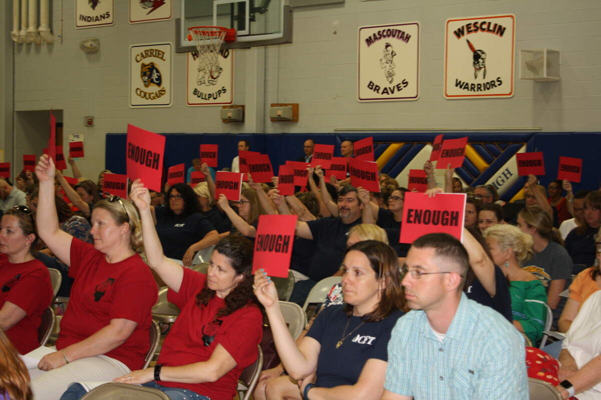 Every time O'Fallon School District 90 board member Steve Springer spoke during the board meeting Tuesday night about 120 teachers held up uniform red signs with black letters reading, 'Enough.'