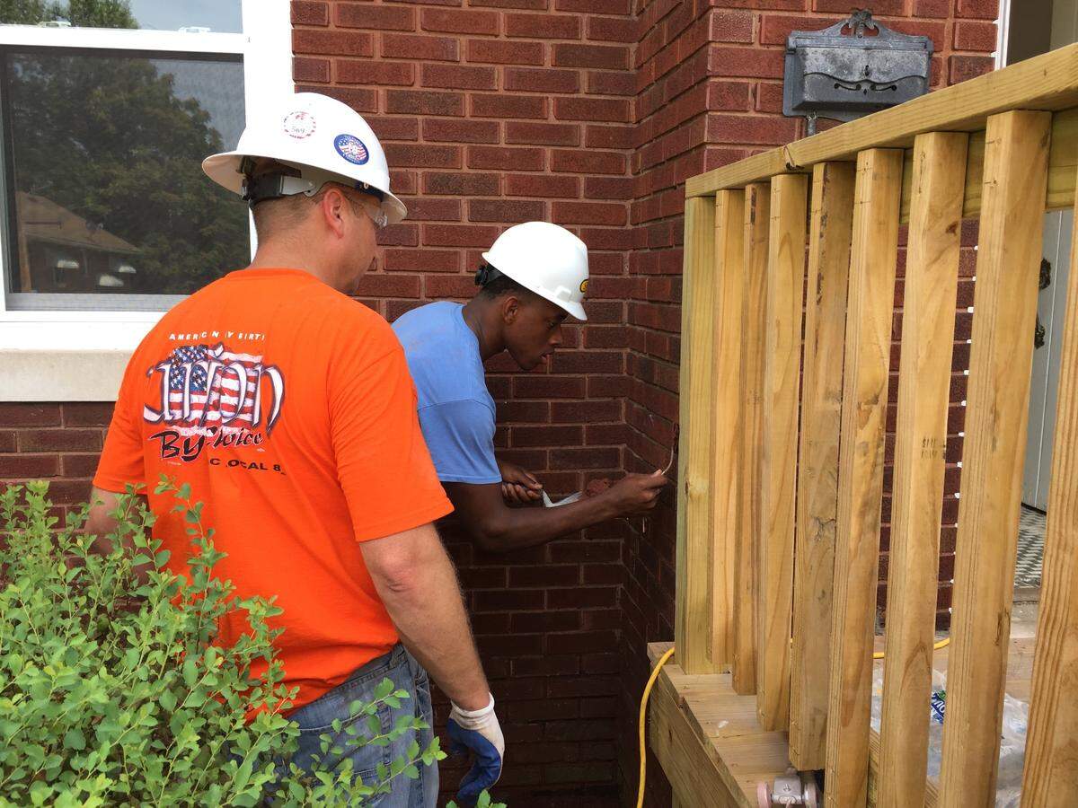 Jordan Wade, right, tuckpoints bricks on a duplex on North 42nd Street in East St. Louis after receiving tips from Matt Braun, president of the Bricklayers Local 8 union on Saturday. Wade, 18, is participating in the East St. Louis-based R3 Development organization, which helps teenagers learn life skills in preparation for a career.