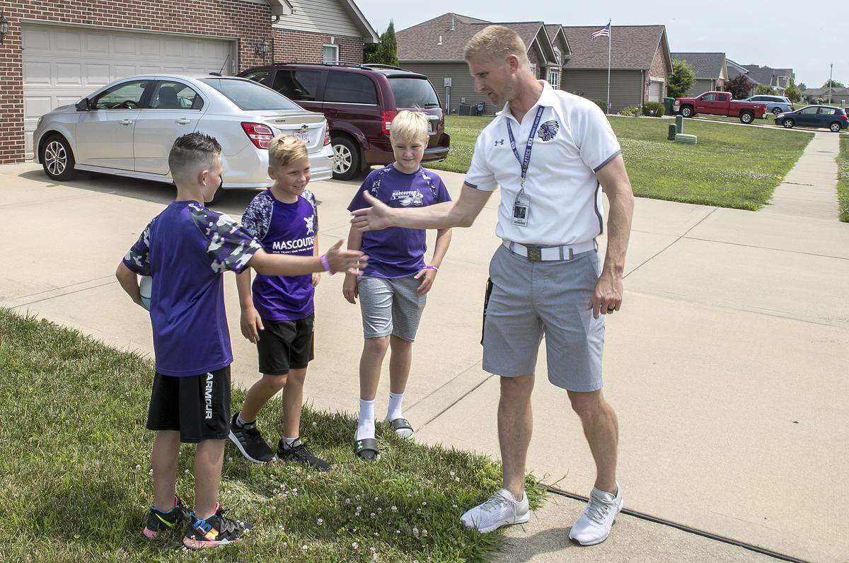 Mascoutah High School athletic director Scott Battas congratulates three boys for being outside. He was making his rounds as part of the M-Town Outdoor Challenge, a community-wide program that encourages kids to play outside.