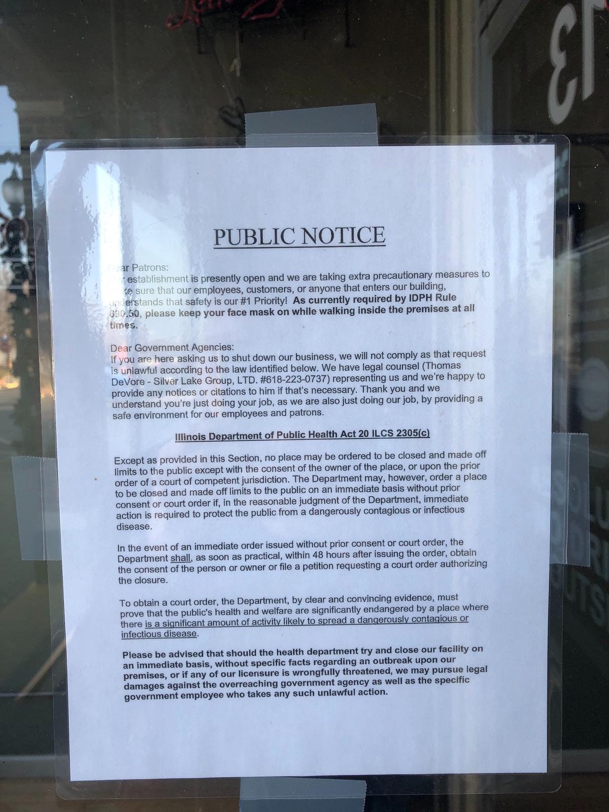 A sign on the door at Shooters Bar & BBQ in downtown O’Fallon warns it will not shut down if ordered to do so by “government agencies.”