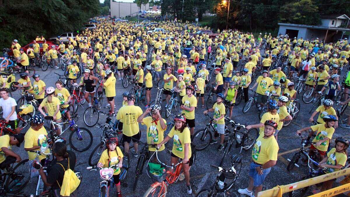 More than 2,300 bicyclists and 200 volunteers participated in the Tour de Belleville ride in 2014. Here, a crowd is shown in matching yellow T-shirts listening to music at the pre-ride party.