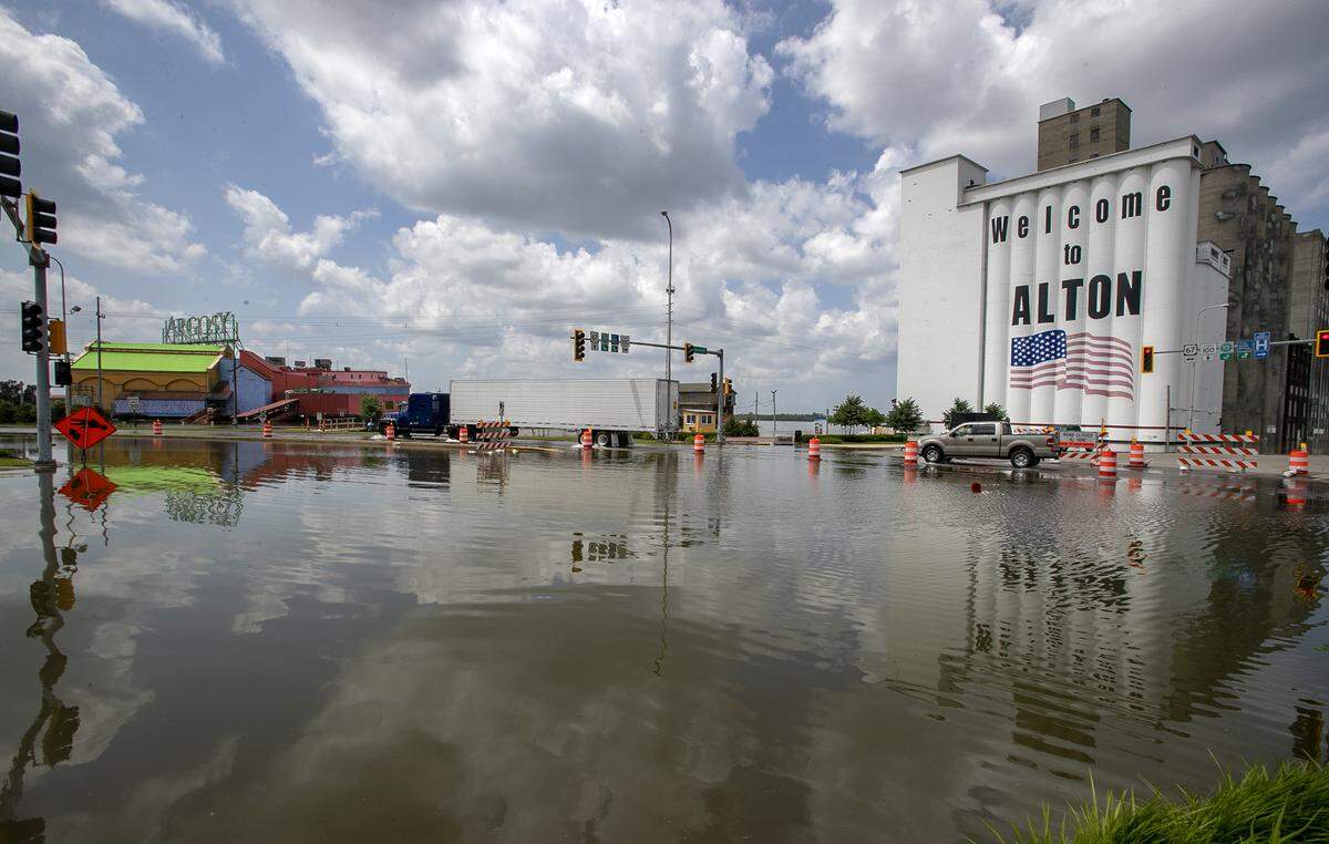 Vehicles drive through standing water on U.S. 67 in downtown Alton. High water has closed the north bound lane at the intersection of Illinois 100 and U.S. 67.