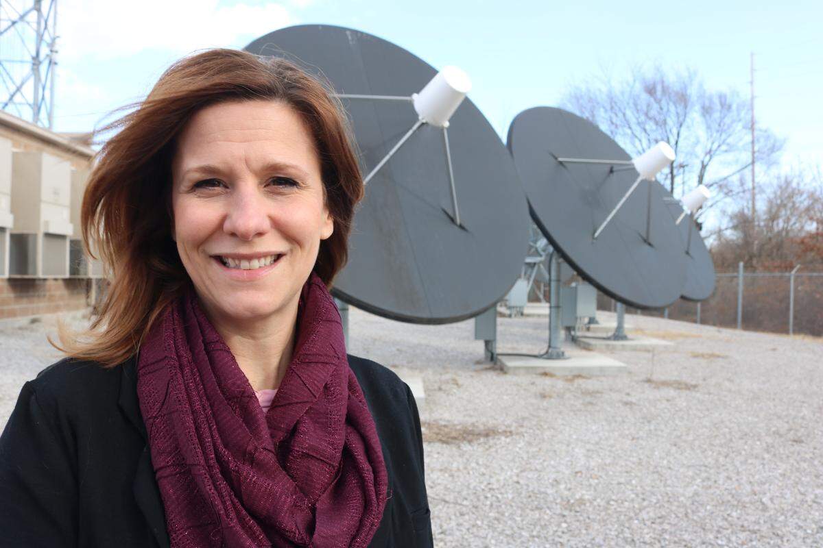 The city’s Director of Technology and Innovation Angela Imming stand in front of giant satellite dishes at Highland Communication Services.