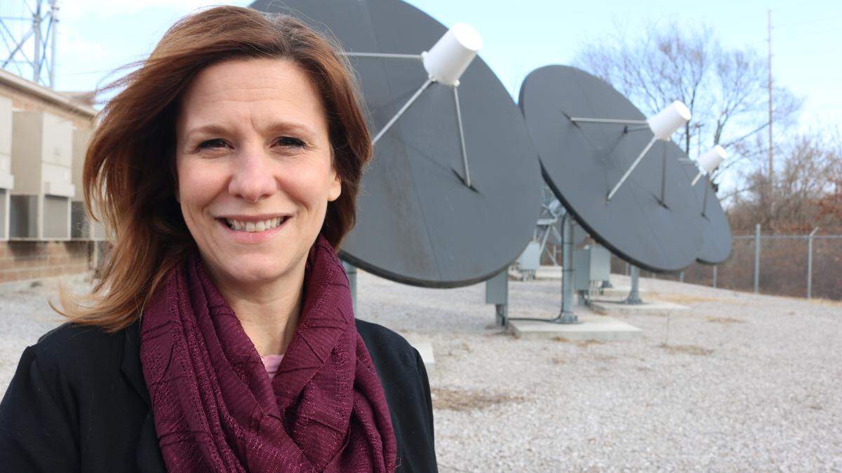 The city’s Director of Technology and Innovation Angela Imming stand in front of giant satellite dishes at Highland Communication Services.