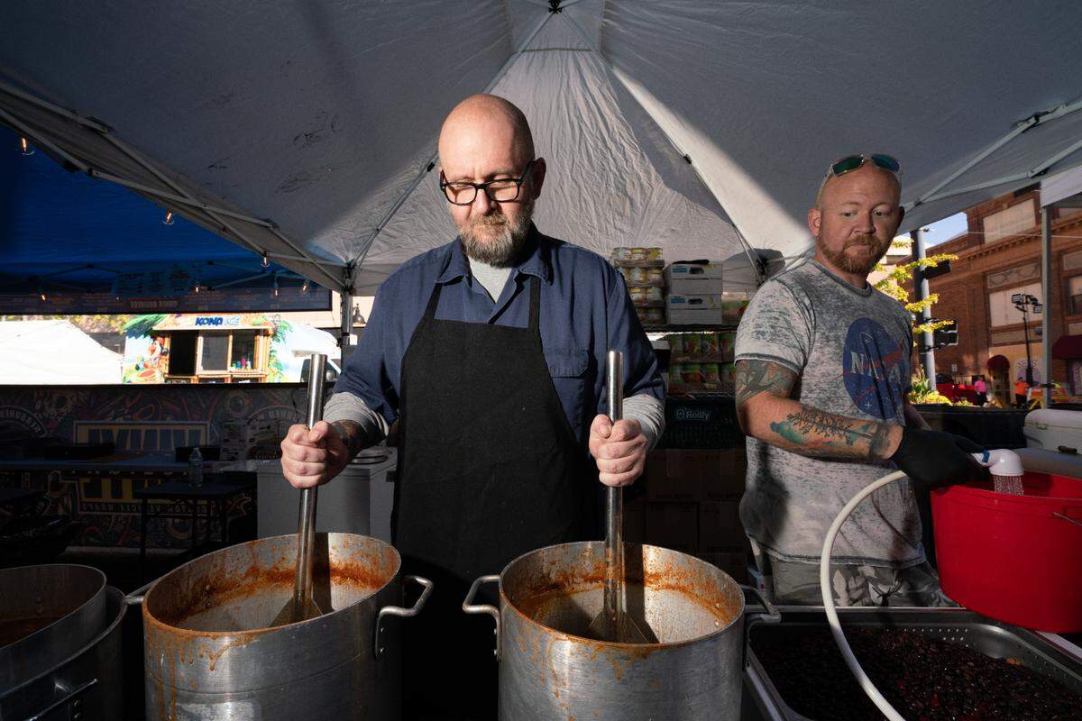 Greg Bach stirs two pots of chili simultaneously while his brother Brian admires his work during last year’s Chili Cook-Off.