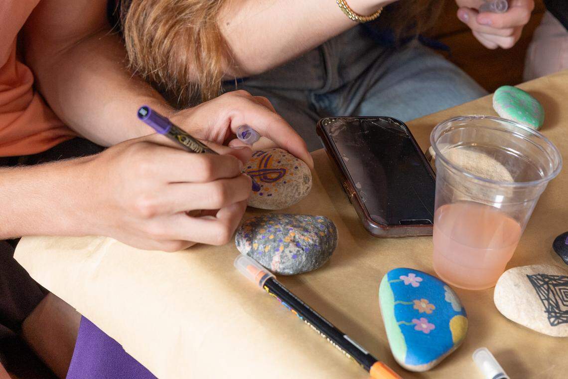 A teen draws a cancer awareness ribbon onto a rock during the celebration of life for Elsie Wiemerslage, who died April 15 from an aggressive form of childhood cancer after a decade-long battle.