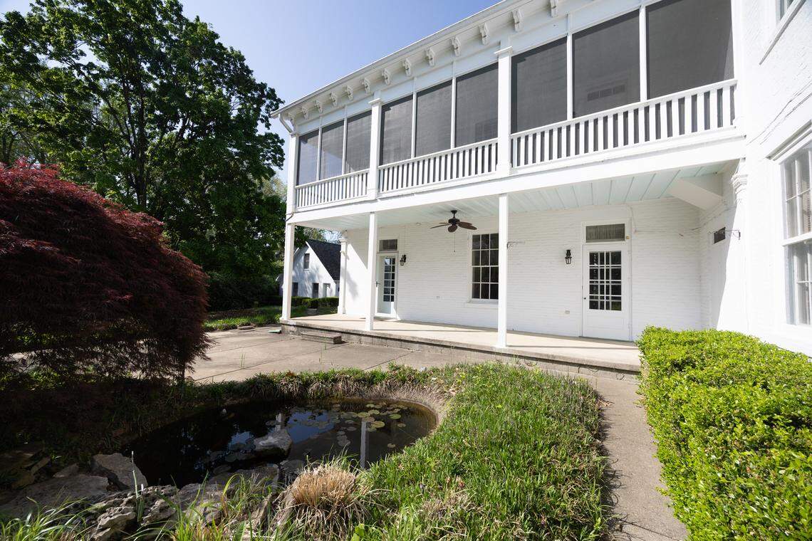 The backyard features a tranquil garden, complete with manicured trees, a peaceful lily pond, and a carriage house.