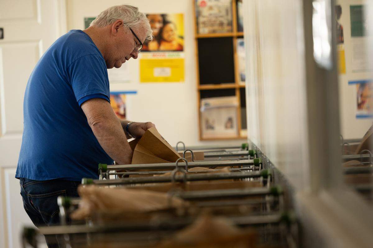 Dan McKenzie fills grocery bags during the afternoon rush at Community Interfaith Food Pantry in Belleville.