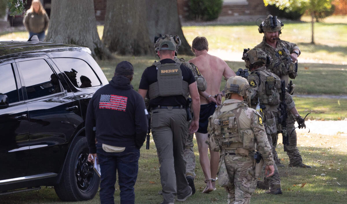 Authorities escort a shirtless and handcuffed suspect after a standoff in the 1800 block of Meadows Dr. in Columbia, Ill.
