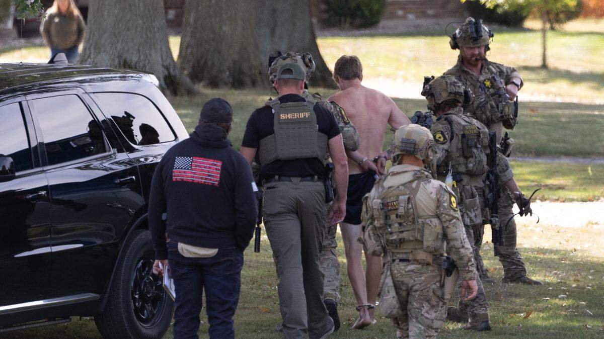 Authorities escort a shirtless and handcuffed suspect after a standoff in the 1800 block of Meadow Court in Columbia.