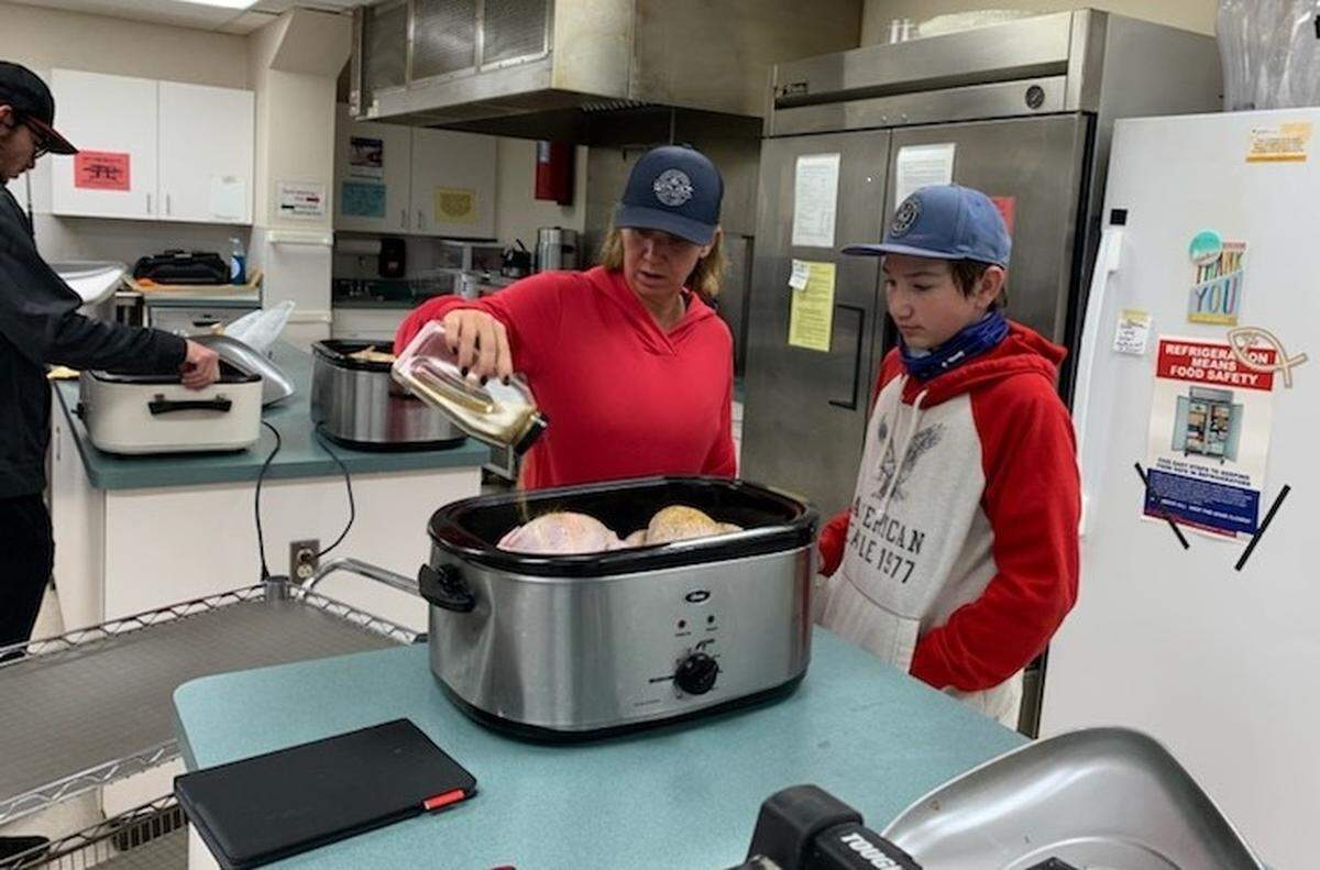 Volunteers, left to right, Braedon Spicer, his mother Christy and brother Nolan start early Wednesday morning preparing for a Thanksgiving dinner drive-thru on Thursday at Faith Lutheran Church in O’Fallon.