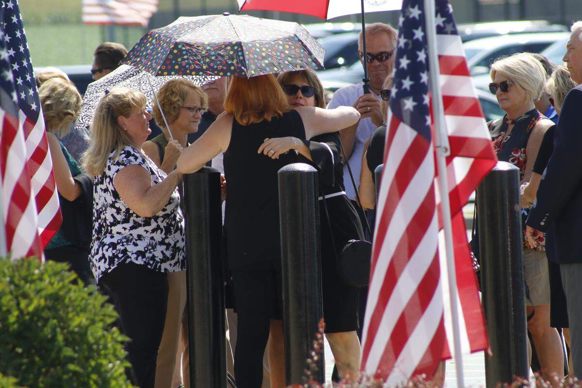 People hug each other while waiting in line to enter the high school auditorium for the visitation of ISP Trooper Nicholas Hopkins.