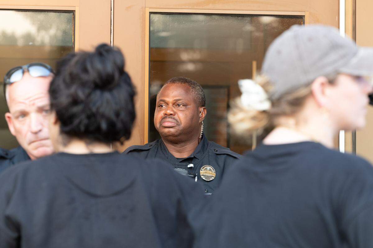 An officer stands outside the Fairview Heights police department during a protest in Fairview Heights on July 24, 2024 against the police killing of Sonya Massey in her Springfield, Ill. home. The protest was taken to the police station after the arrest of the protest leader and organizer, J.D. Dixon.