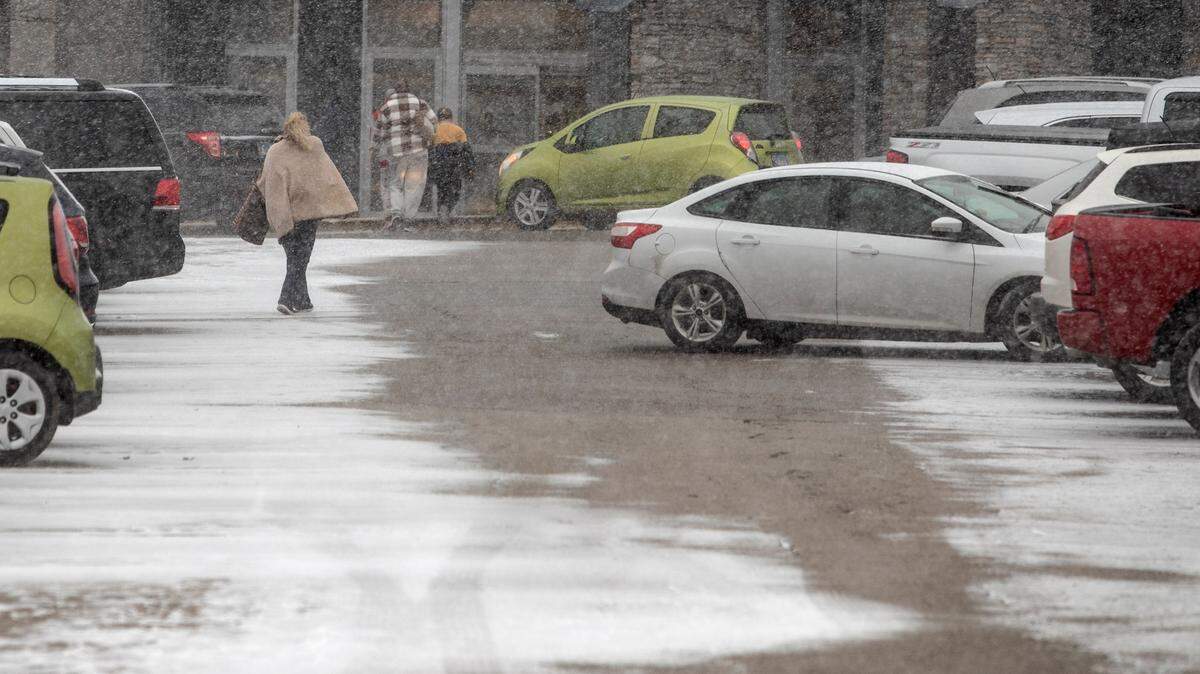 Shoppers head into St. Clair Square just before noon on Thursday as temperatures started to drop with gusty winds, snow and sleet.