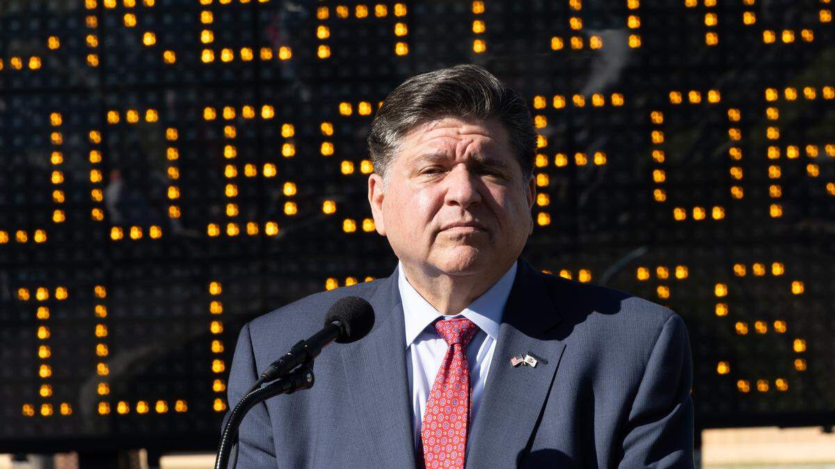Ill. Gov. J.B. Pritzker stands in front of a road sign reading “creating jobs for Illinois” during a news conference for the Rebuild Illinois project in Fairmont City on Oct. 20, 2025.