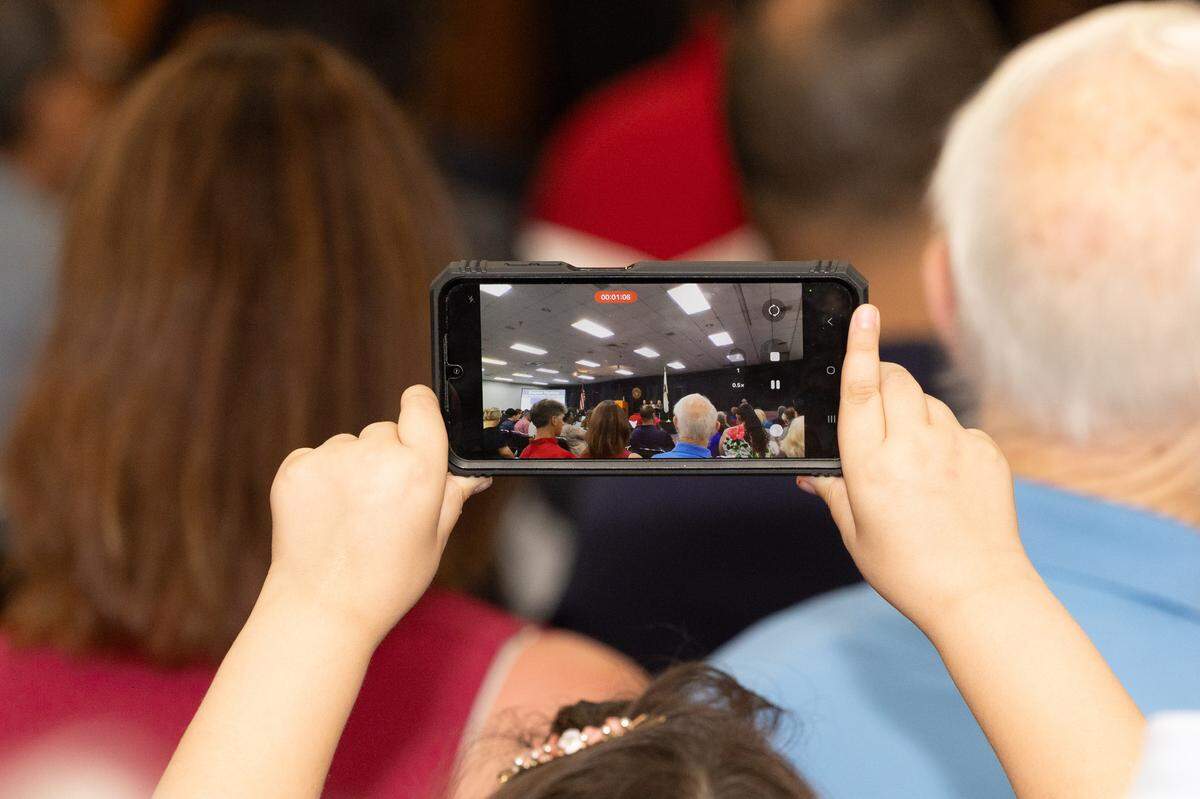 A child films their relative as they accept their citizenship certificate at a naturalization ceremony in Collinsville.