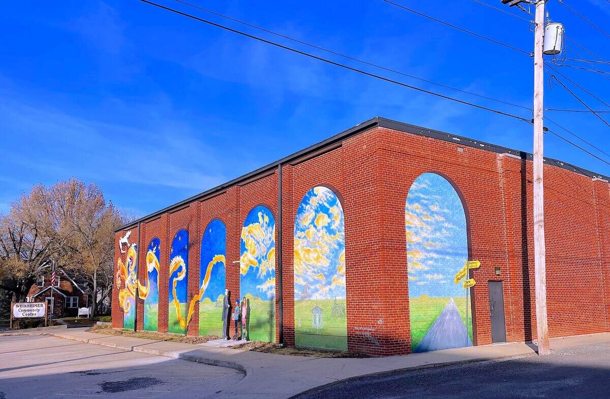 Made possible in part by a $10,000 matching grant from the National Endowment for the Arts, a mural was designed and painted on the side of the Weinheimer Community Center at the corner of Main and Pine Streets in Highland, by Robert and Liza Fishbone of On the Wall Productions from St. Louis. They were assisted onsite by Andy Cross (set painter for The St. Louis Muny Opera), and Lisa Roth. Deborah “Moe” Moellering painted the three cut out figures installed next to the mural.