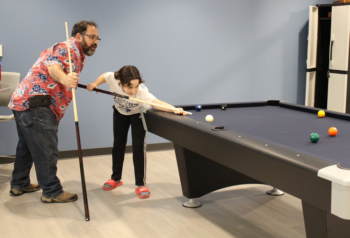 Lewis Thomasino, left, gives some pool tips to his 12-year-old daughter, Gemma, in a game room at The Rec, a new $21 million recreation center in Fairview Heights.