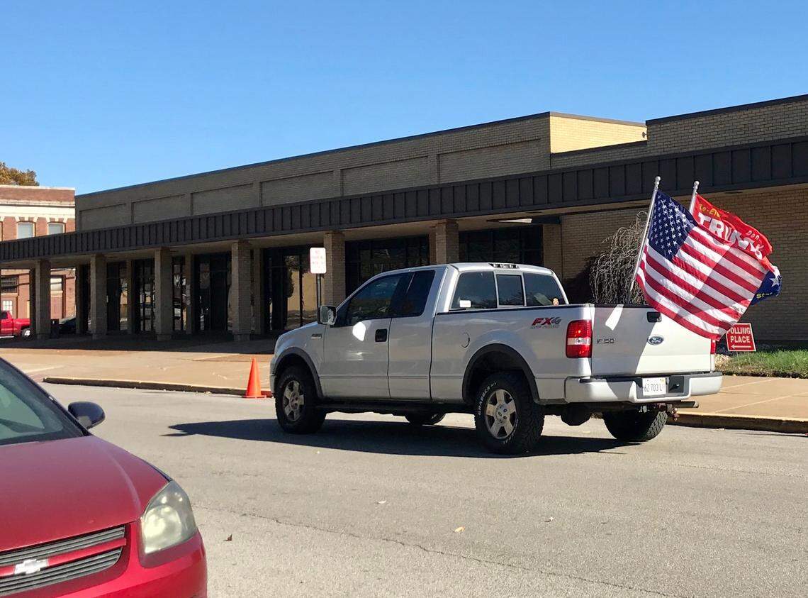 A supporter of President Donald Trump cruises by a polling place at the Granite City Township building on Tuesday, flying an American flag and Trump flag from the back of his pickup truck.