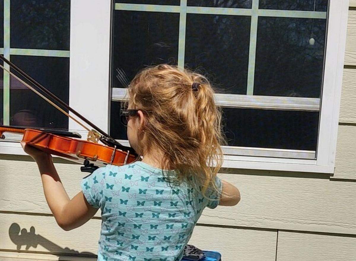 Madelyn, 9, plays the violin outside her great-grandfather Roscoe’s room at Cedarhurst of Shiloh.