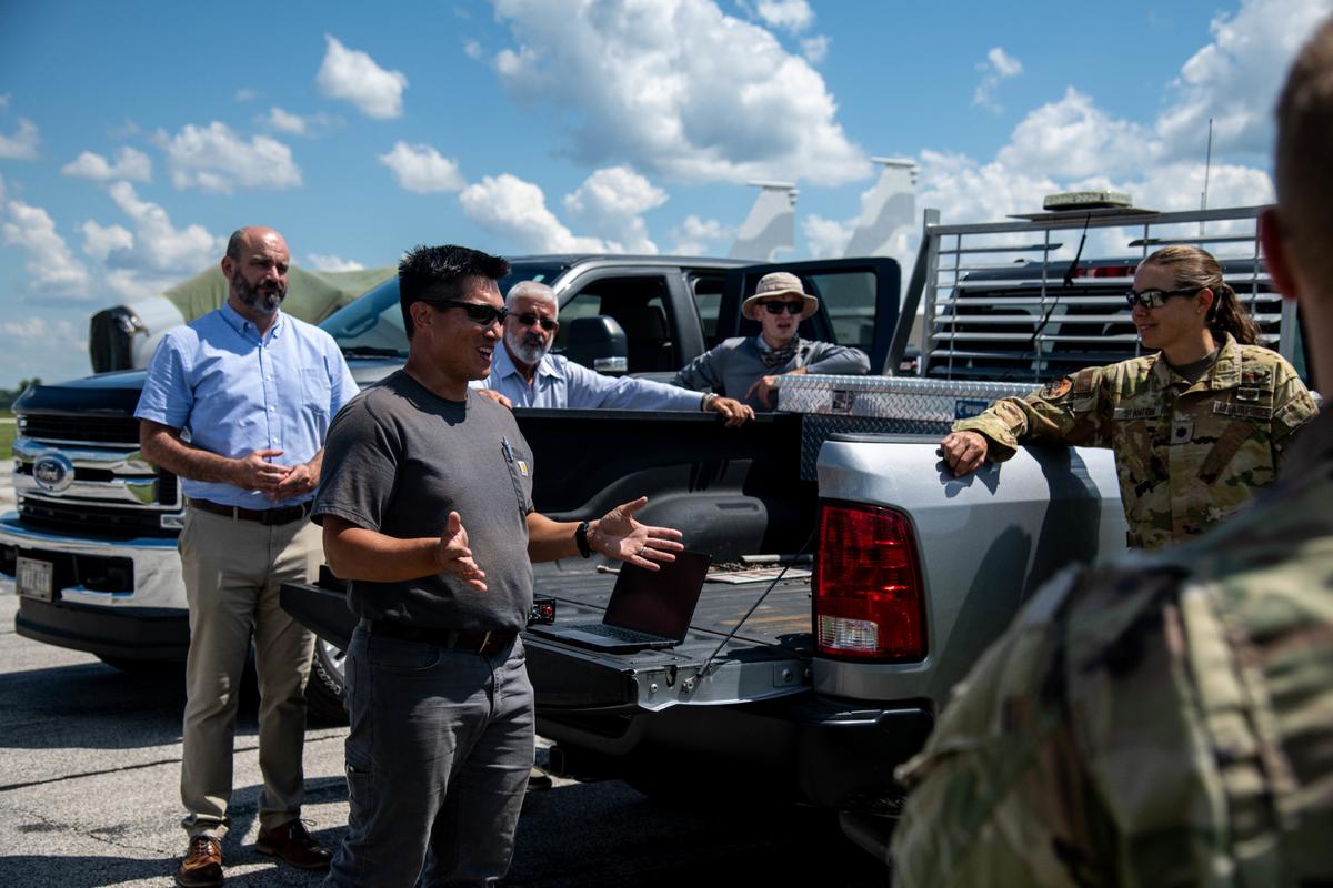 Cory Spaetti, Sabanto Agriculture lead engineer, briefs members of the 375th Civil Engineer Squadron during an operational demonstration of an autonomous tractor on the flight line on Scott Air Force Base. During the demonstration, two tractors worked in tandem to both mow a section of a field as well as pick up pieces of foreign objects and debris.