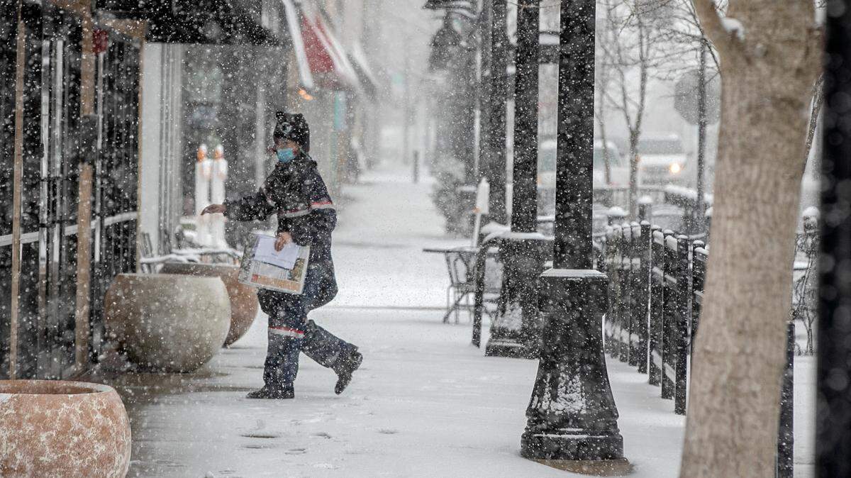 A mail carrier delivers to a downtown Belleville business Wednesday just before noon as snow blanketed most of the region.
