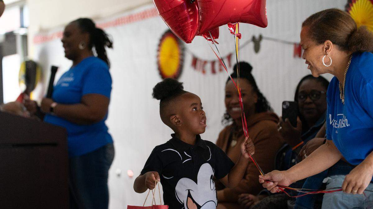 Vera Edwards hands Damon Ward. Jr. a handful of balloons to celebrate the Make-A-Wish trip to Disney World during an assembly at East St. Louis’s Dr. Katie Harper Wright Elementary School on Oct. 23, 2023.