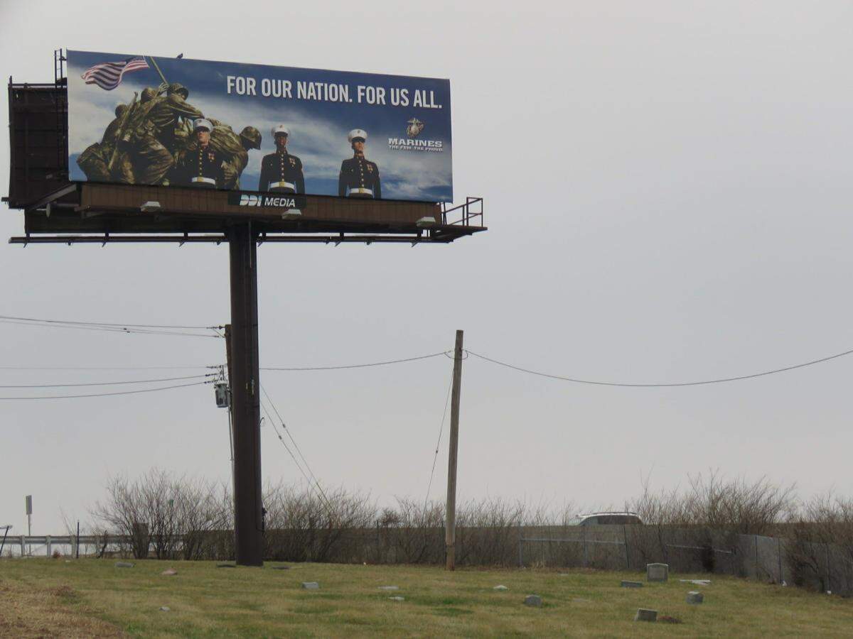 A billboard for the U.S. Marines towers over graves in the historically black Washington Park Cemetery in St. Louis. The leader of an activist group has filed a lawsuit to get them removed.
