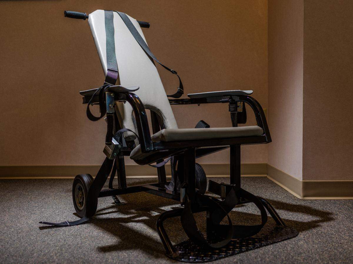 A restraint chair made by E.R.C. Inc. can be seen. The company, now known as Safety Restraint Chair Inc., previously faced scrutiny for the use of its chairs at Guantánamo Bay.
