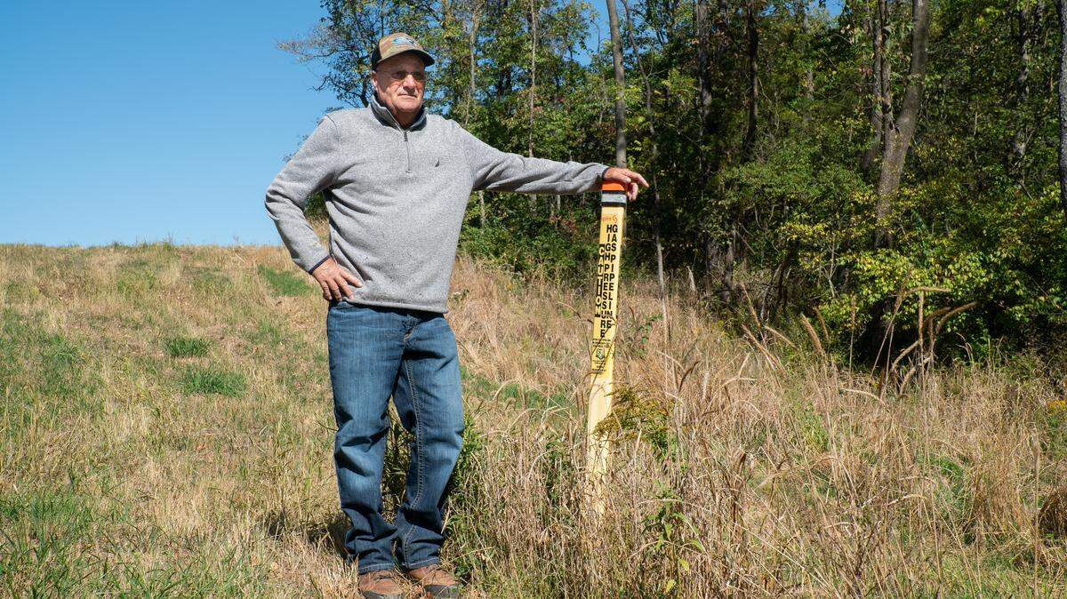Kenny Davis stands next to the yellow tag marking where a natural gas pipeline traverses underneath his Scott County, Illinois farm on Oct. 9, 2023.