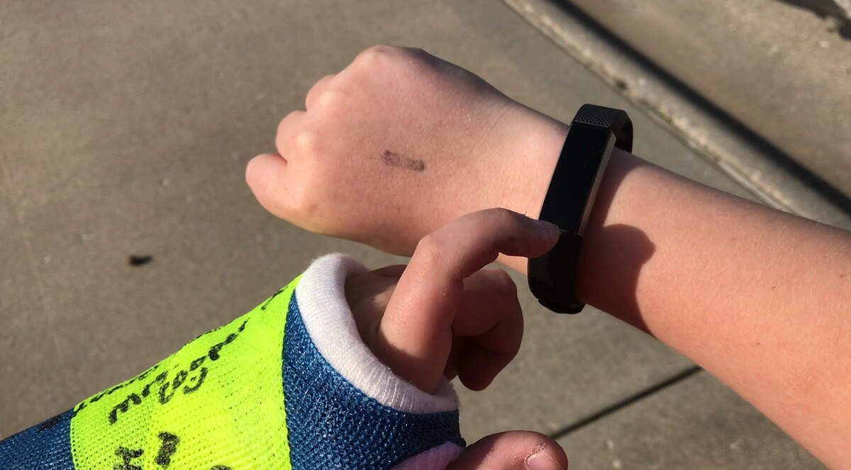 Andy Ord, 13, taps the screen of his new FitBit Charge that scrolls through the time, date, steps walked, miles walked and calories burned. Ord won the FitBit in a year-long bet with former O'Fallon Mayor Gary Graham after loosing more than 10 pounds in a year.