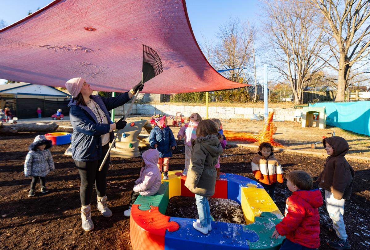 Mary Pender, a teacher at OWL, pushes snow off an awning.